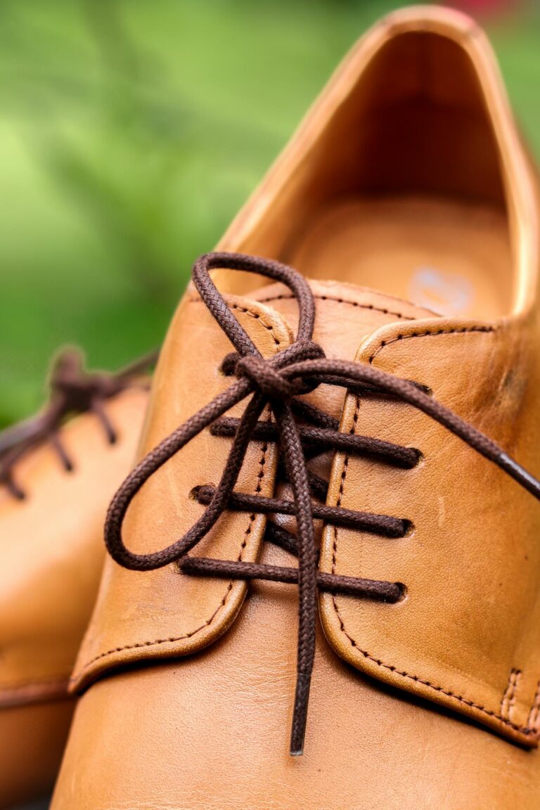 Close-up of tan leather shoes with brown shoelaces outdoors.