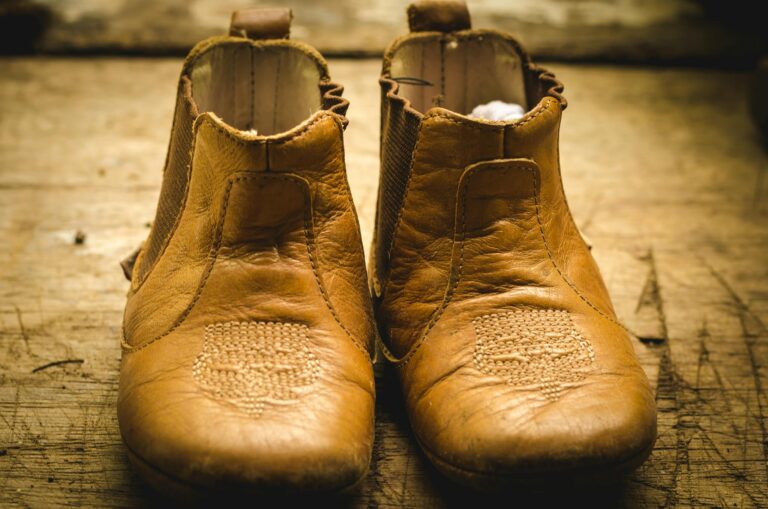 Pair of worn, vintage leather boots displayed on a rustic wooden surface. Perfect for fashion themes.